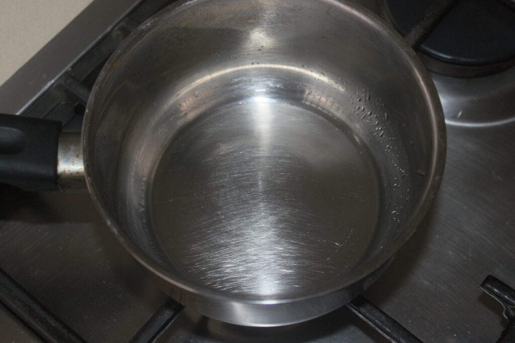 Marmite en acier inoxydable avec de l'eau sur une cuisinière à gaz, vue d'en haut.