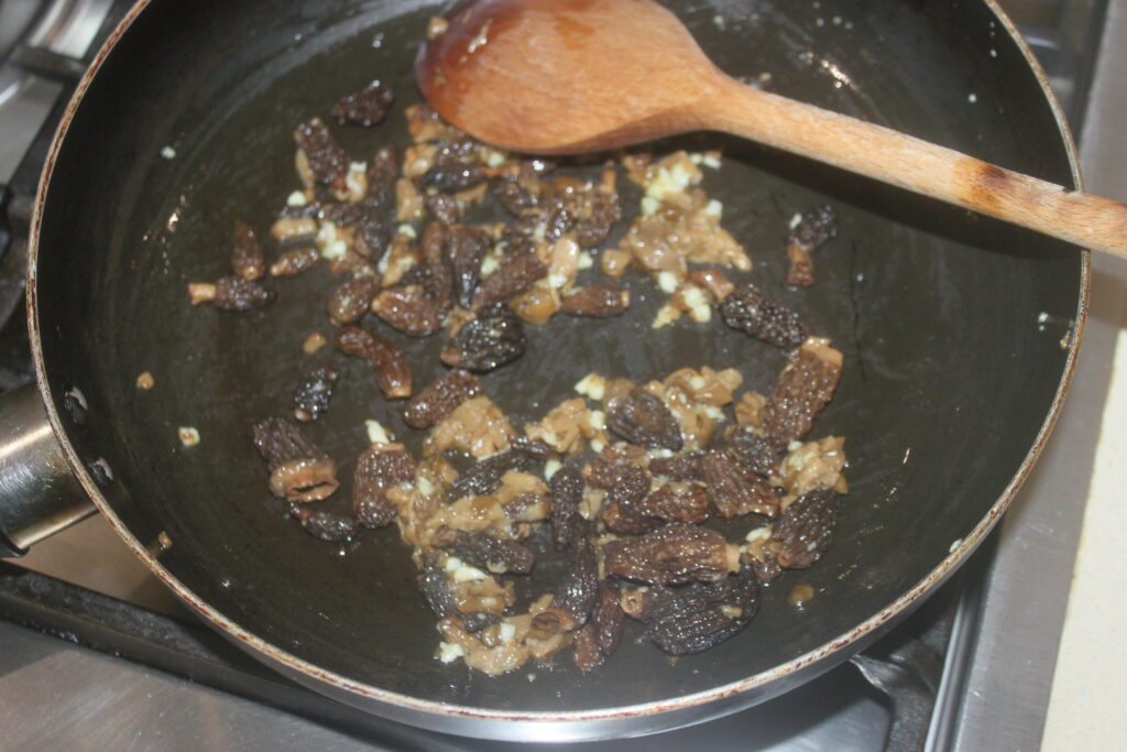 Faire revenir les morilles et l'ail dans une poêle noire avec une cuillère en bois.