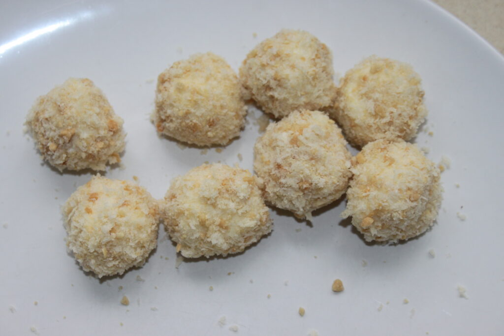 Ocho bolas de Mozza empanadas y fritas dispuestas en un plato blanco, perfectamente complementadas con una guarnición de mayonesa de wasabi.