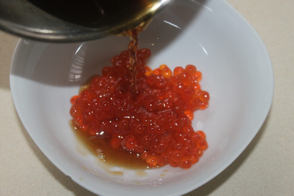 Sauce soja versée sur un bol d'œufs de poisson rouge.