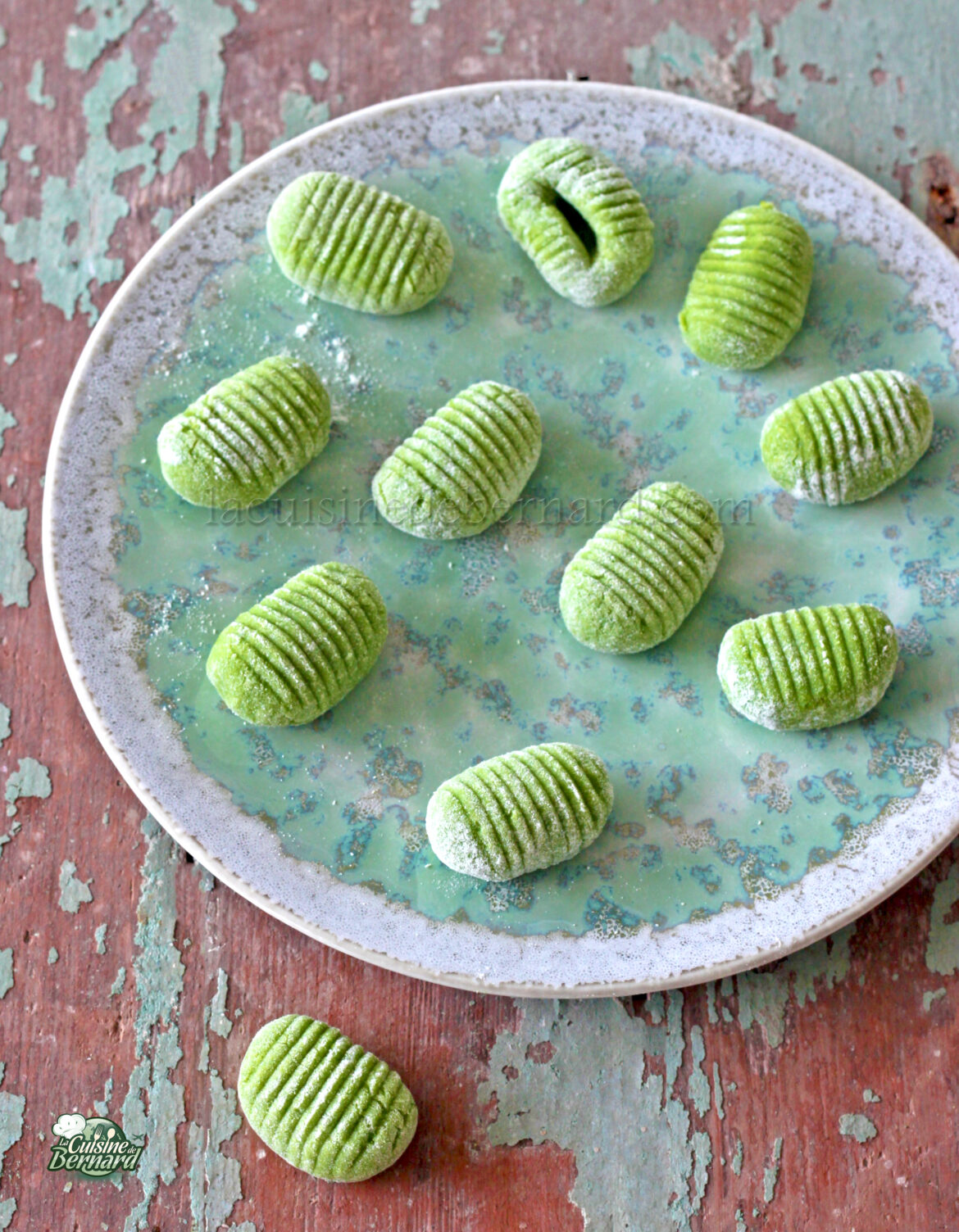 Ñoquis verdes en un plato sobre una mesa de madera.